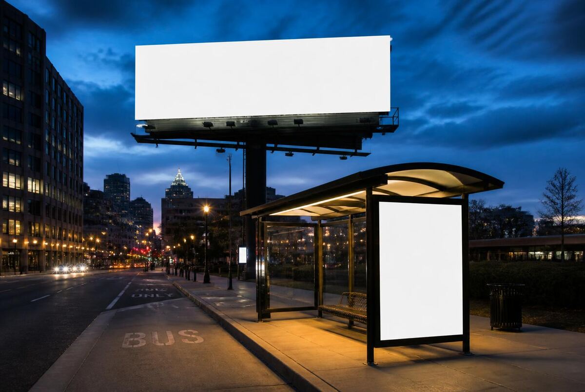 Illuminated bulletin and transit shelter advertising panels at dusk in a downtown American city